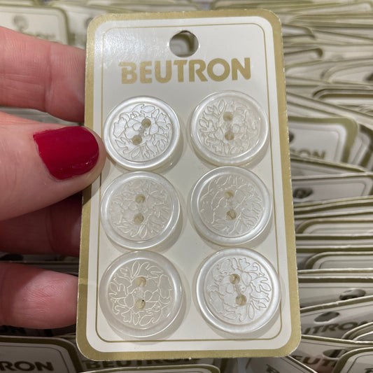 Packaging of buttons with 'Beutron' branding held by a hand.