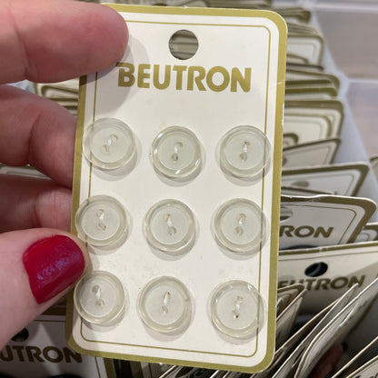 Packaged buttons with 'Beutron' branding held by a hand.