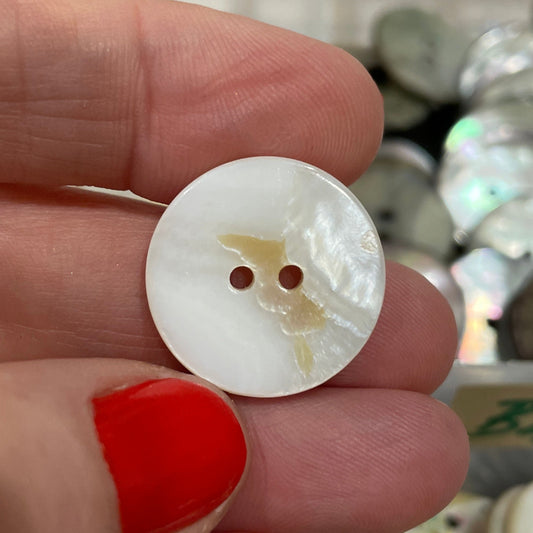 Hand holding a white button with a blurred background of button display