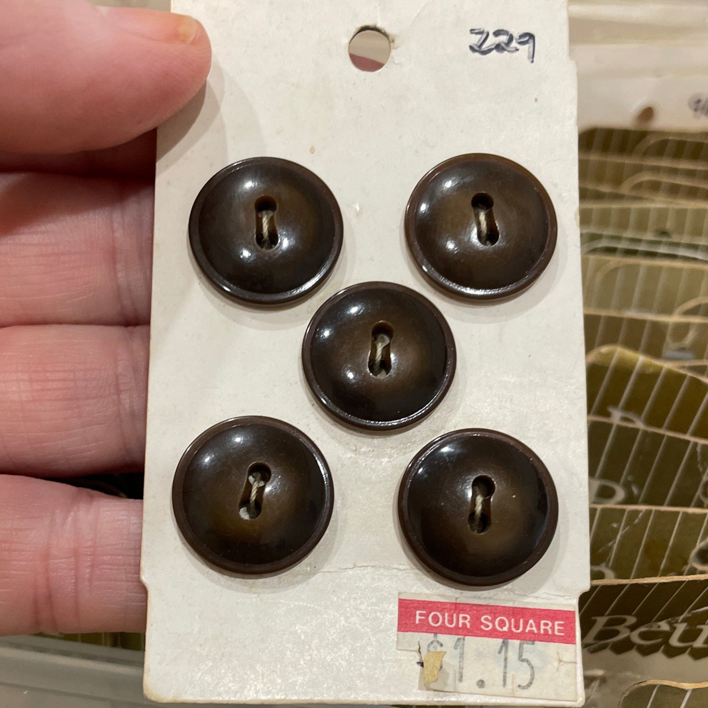 Hand holding a card with five buttons against a blurred background