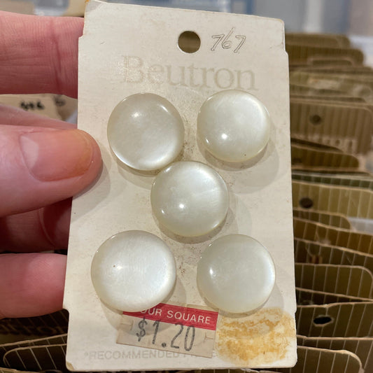 Hand holding a package of white buttons with a blurred background