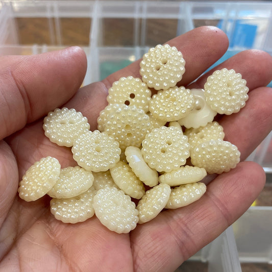 Hand holding a small pile of white beads with a blurred background