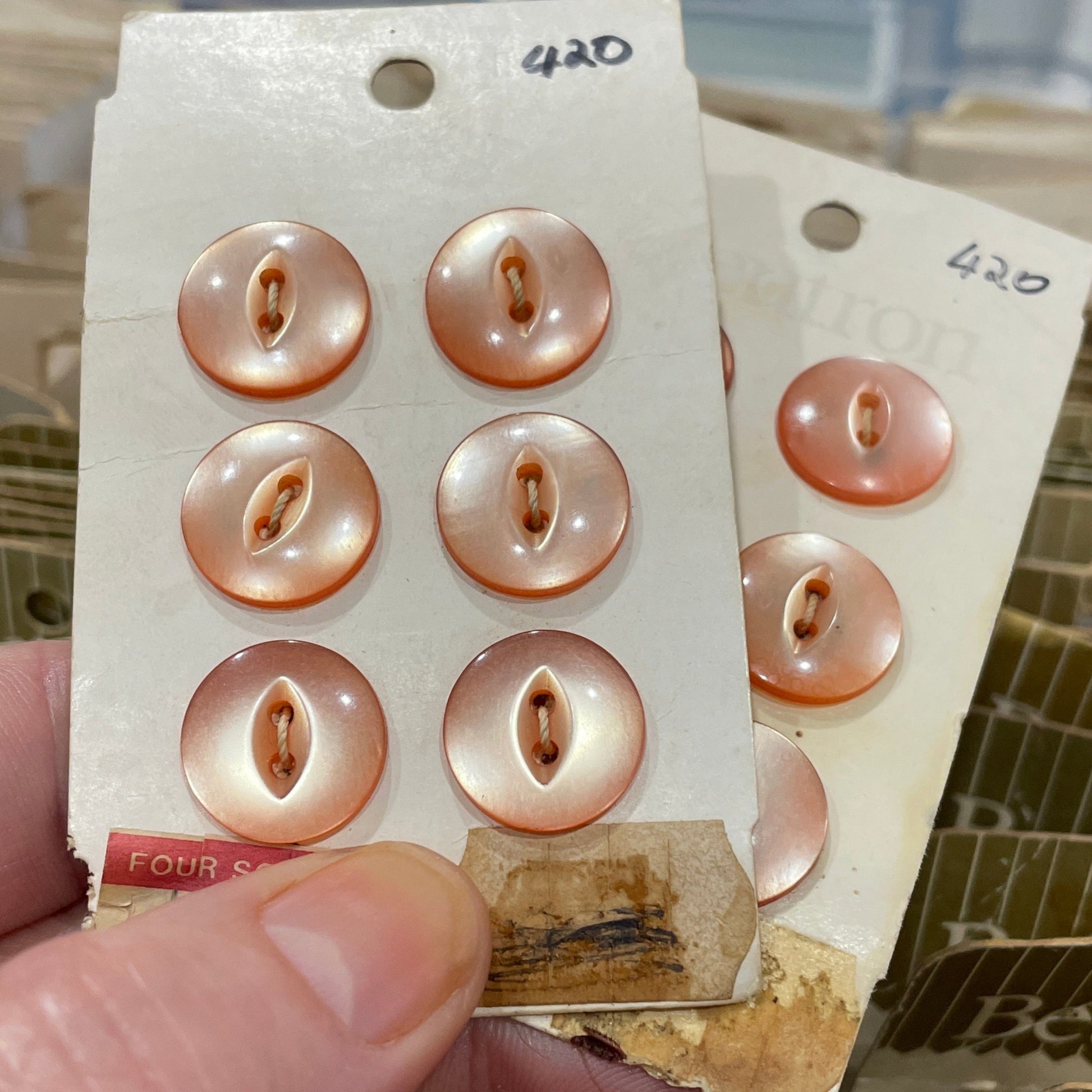 Hand holding a card with rose gold buttons against a blurred background