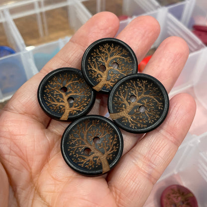 Hand holding decorative buttons with a container of more buttons in the background