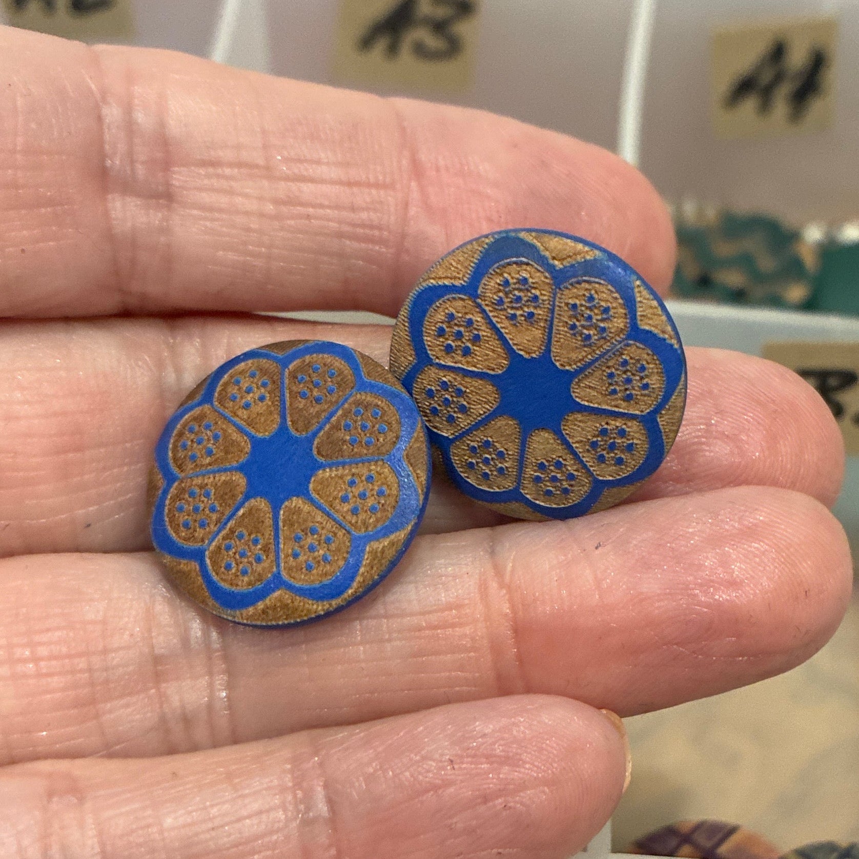 Hand holding blue decorative buttons with a background of button collection