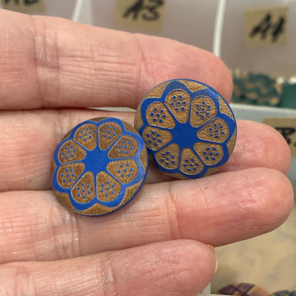 Hand holding blue decorative buttons with a background of button collection