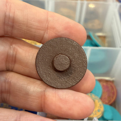 Hand holding a round button with a blurred background of storage containers.