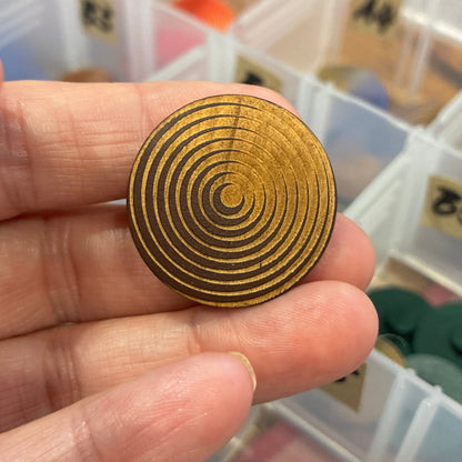 Gold spiral design held by a hand with a background of color swatches.