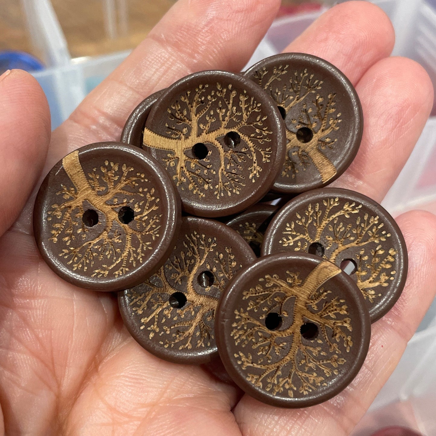 Hand holding a collection of ornate brown buttons with a blurred background