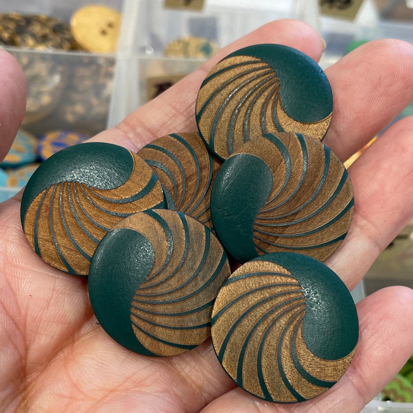 Hand holding green decorative buttons with a blurred background of more buttons.
