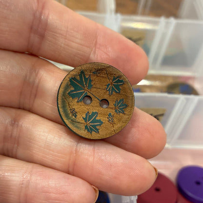 Hand holding a decorative button with a blurred background of button collection