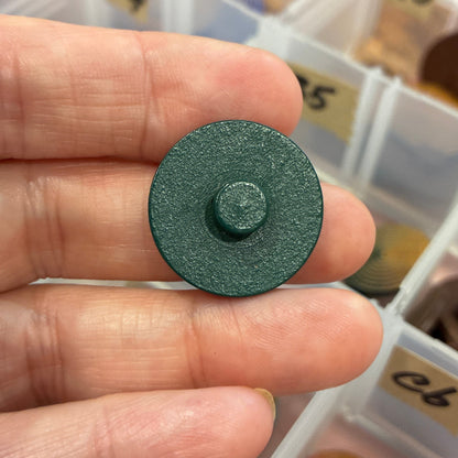 Person holding a green button with a button organizer in the background