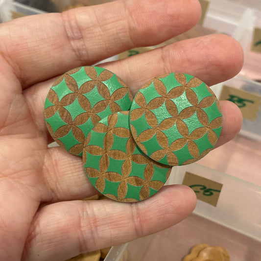 Hand holding decorative buttons with a display case of various buttons in the background.