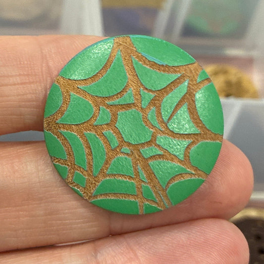 Hand holding a green and gold decorative item with storage containers in the background