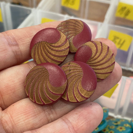 Hand holding red and gold buttons with a background of button containers.