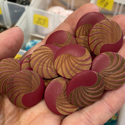 Hand holding red decorative buttons with a container of various buttons in the background.