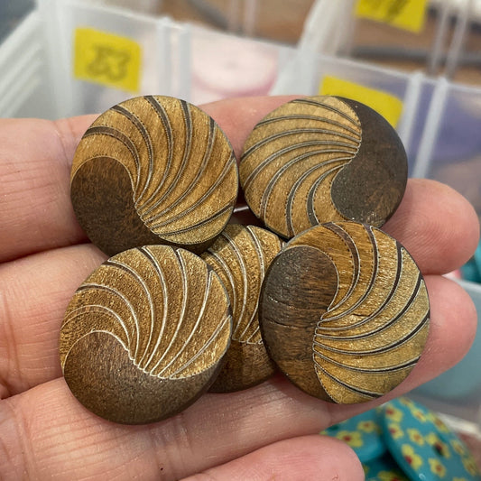 Hand holding wooden buttons with a background of labeled containers.