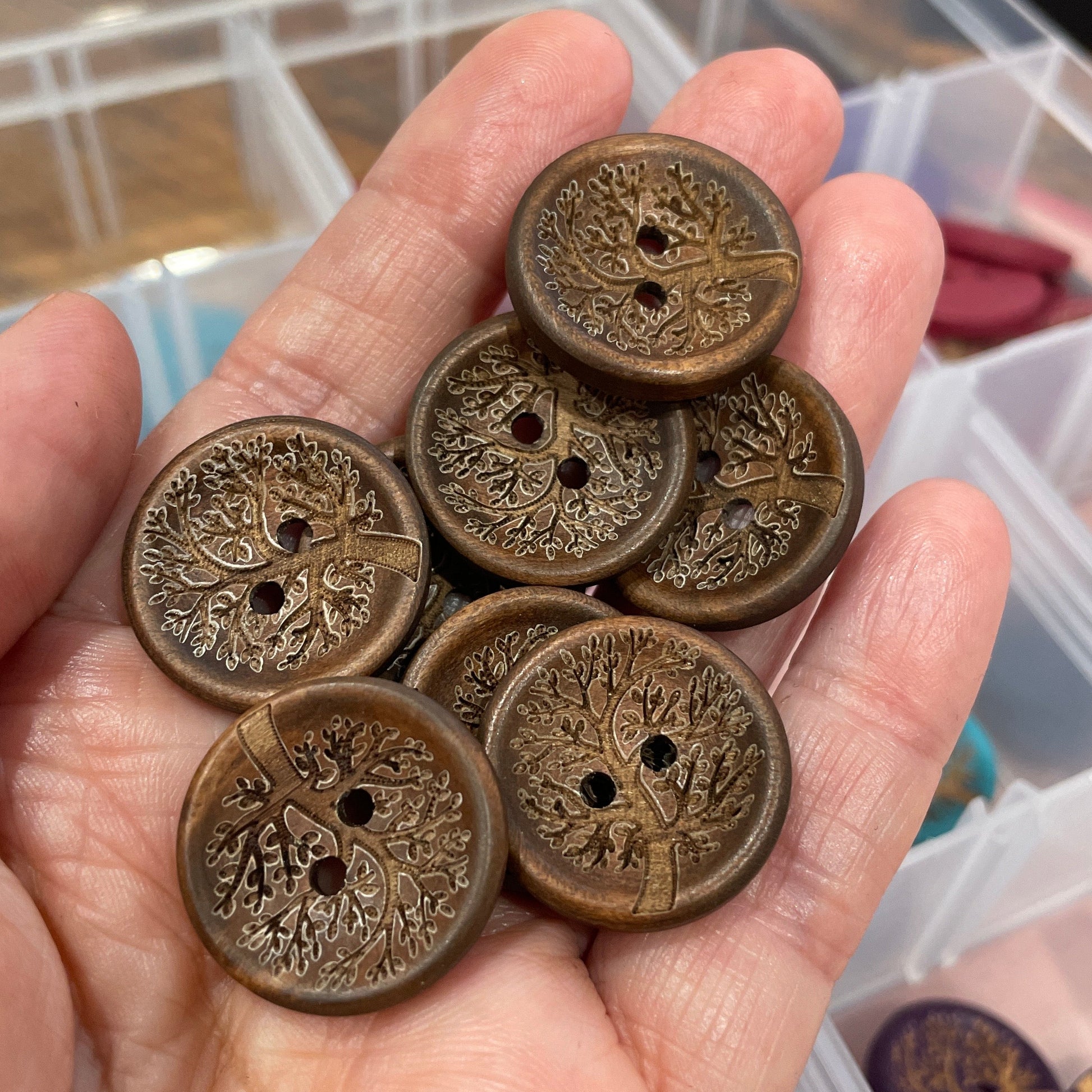 Hand holding a collection of ornate bronze buttons with a blurred background