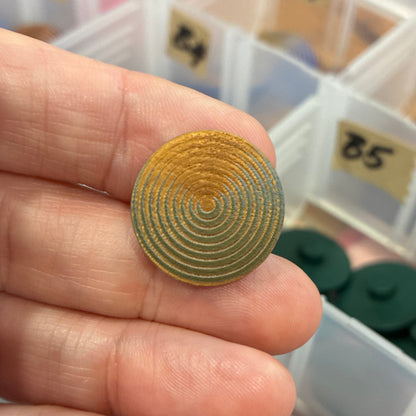 Gold circular button held by a hand with a background of labeled compartments containing various items.
