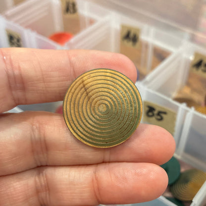 Gold button held in hand with a container of assorted button in the background