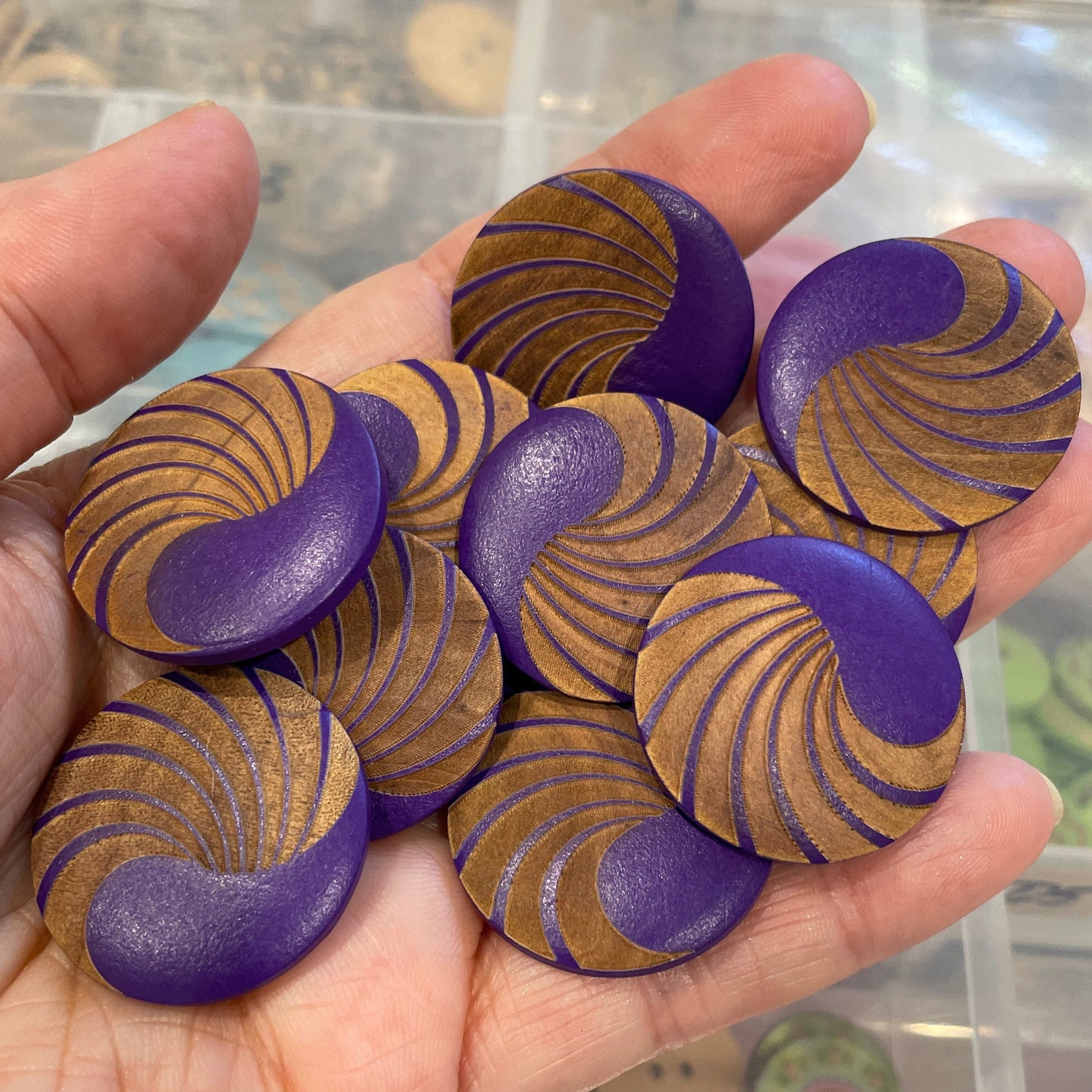 Hand holding purple and gold patterned buttons with a blurred background