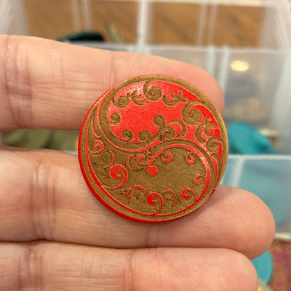 Hand holding a decorative button with a colorful background of storage containers.