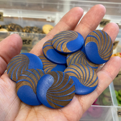 Hand holding blue and gold patterned objects with a blurred background of similar items.