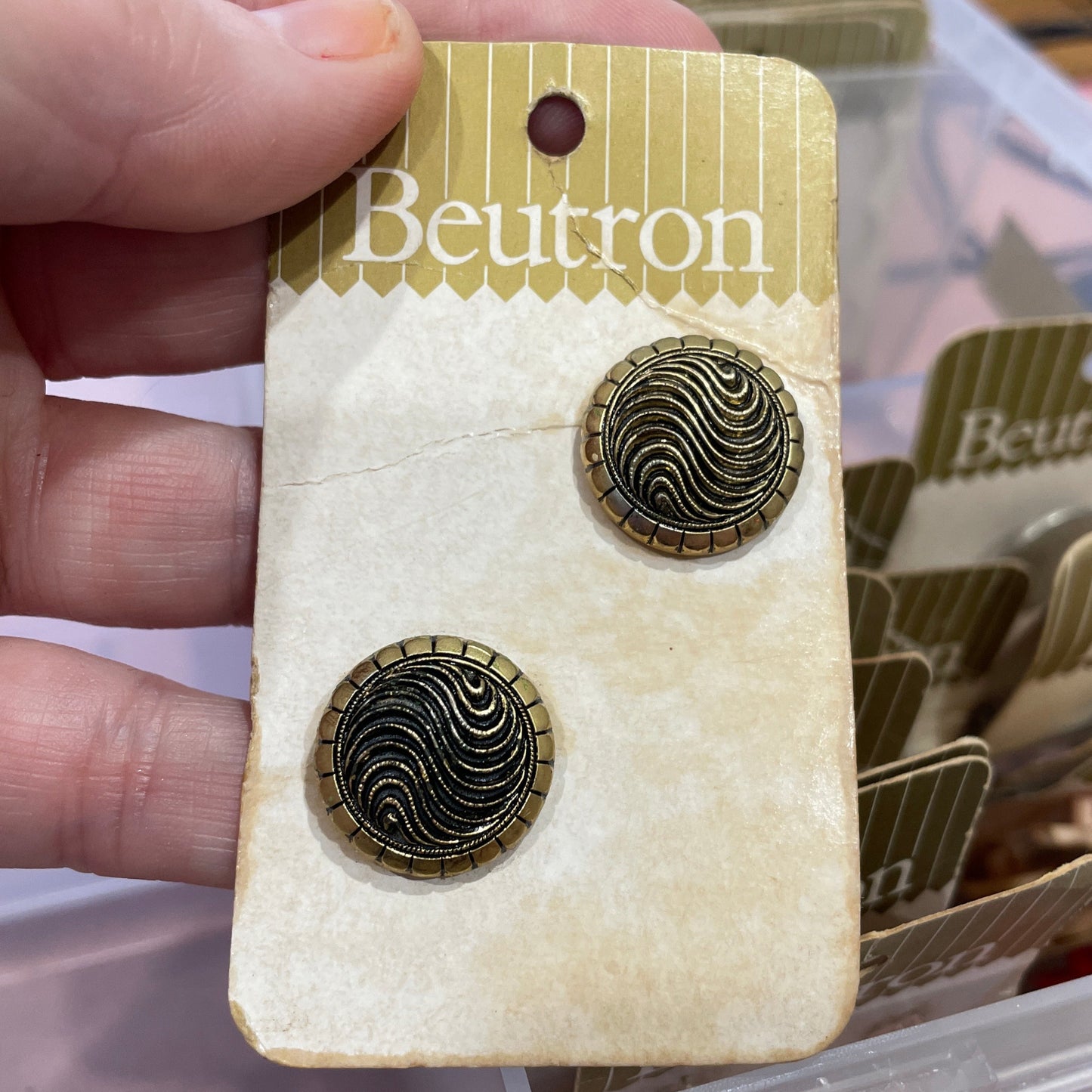 Gold buttons on a card held by a hand with a blurred background
