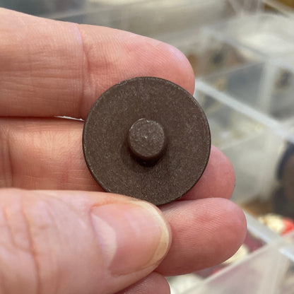 Hand holding a button with a clear container of items in the background