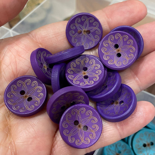 Hand holding purple buttons with a container of blue buttons in the background