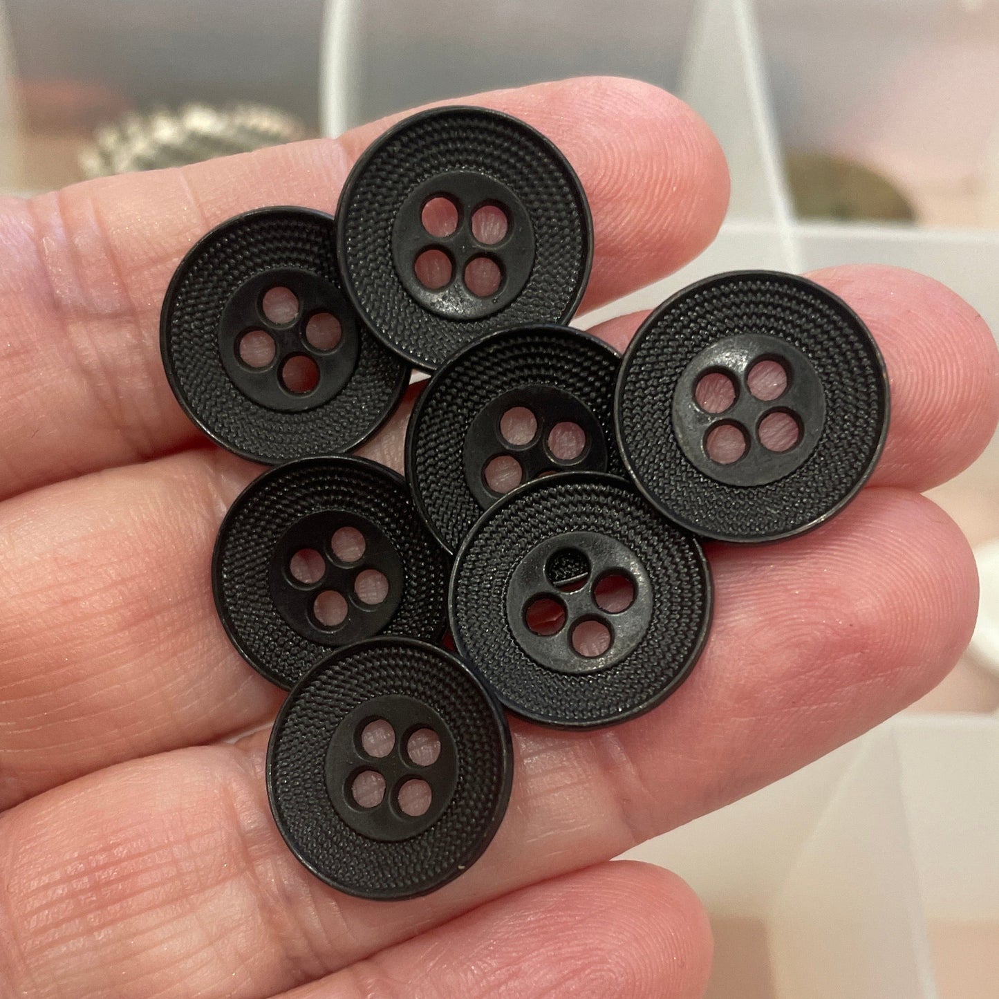 Hand holding six black buttons with a blurred background