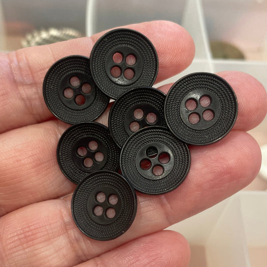 Hand holding six black buttons with a blurred background