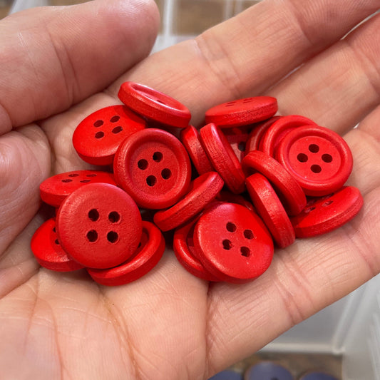 Hand holding red buttons with a container of buttons in the background