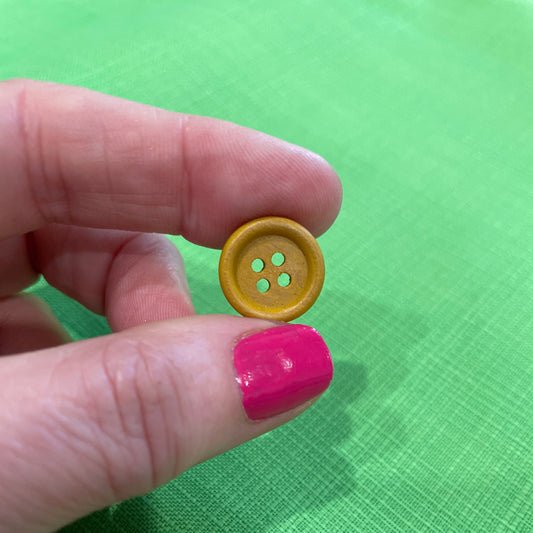 Yellow button held between fingers against a green background