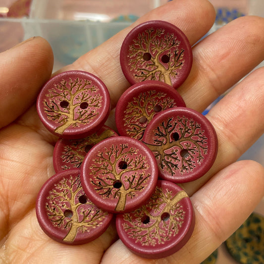 Hand holding decorative buttons with a clear container of more buttons in the background