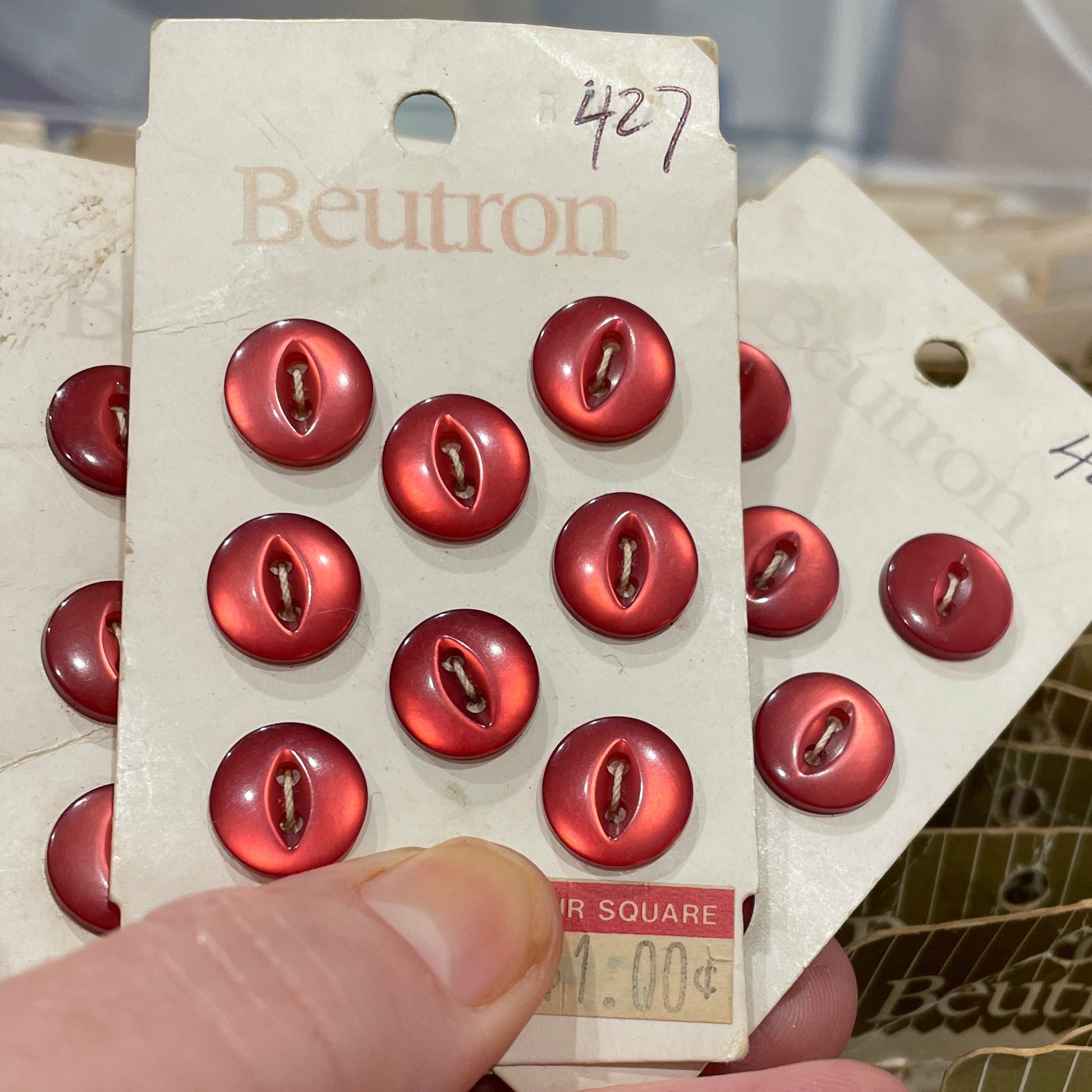 Hand holding a card with red buttons and 'Beuton' branding.