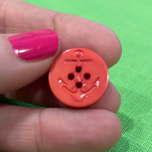 Hand holding a red button against a green fabric background