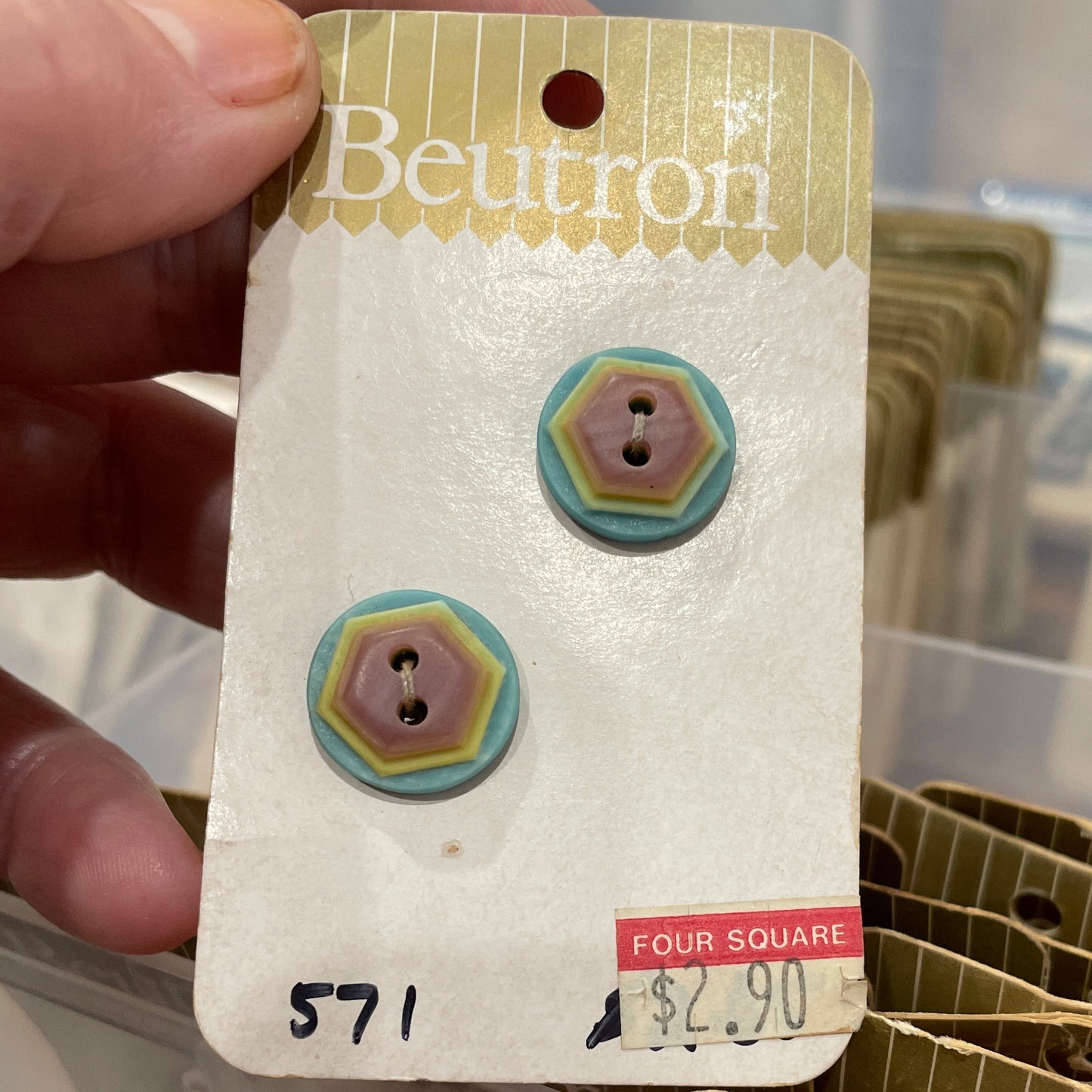 Button card held by a hand, with a blurred background of more cards.
