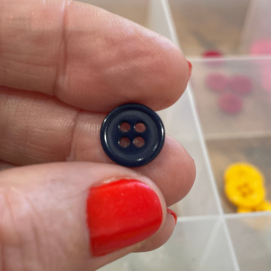 Person holding a black button with a clear container of buttons in the background
