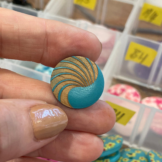 Hand holding a decorative button with a button collection in the background