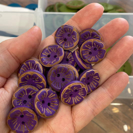 Hand holding purple buttons with a clear container in the background