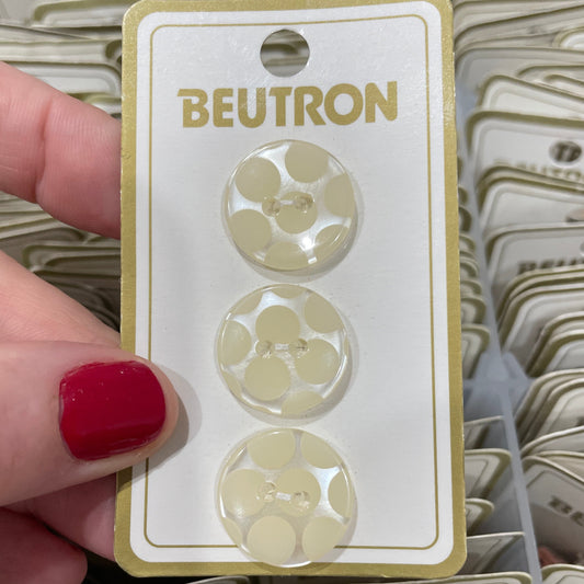Beutron buttons on a card held by a hand with red nail polish, surrounded by more cards.