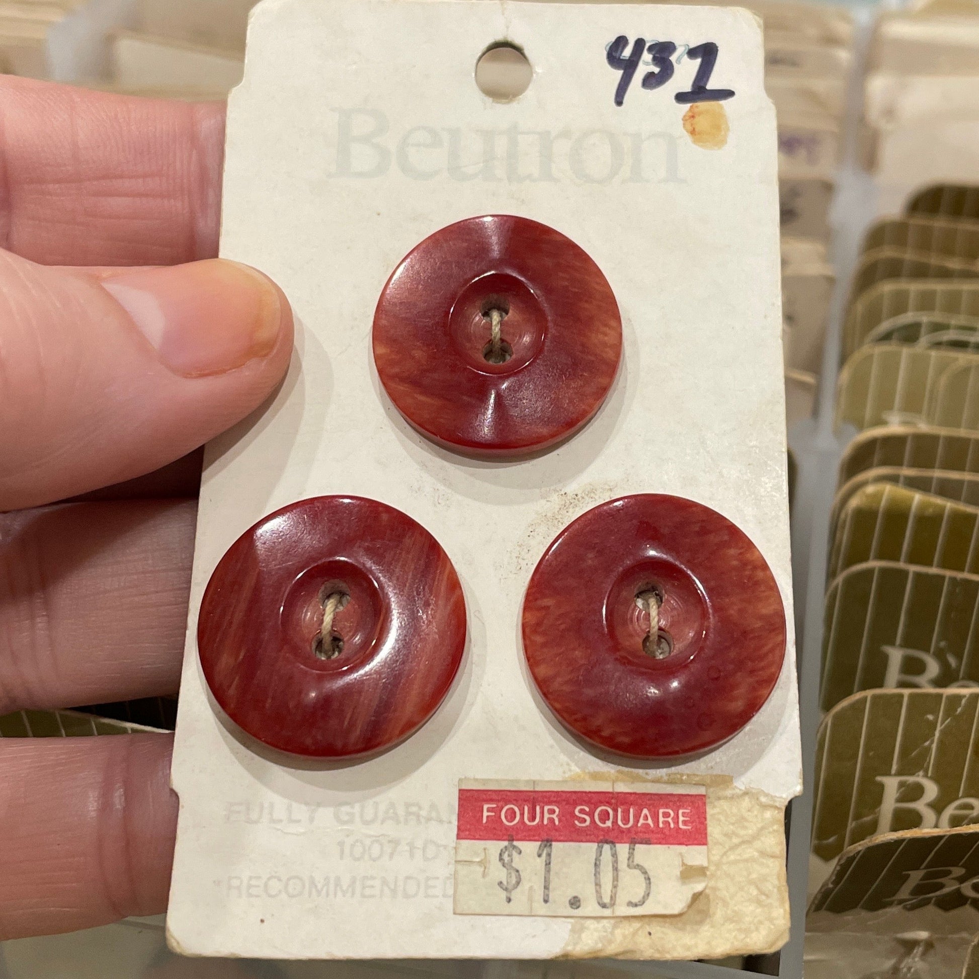 Three red buttons on a white card held by a hand with a blurred background