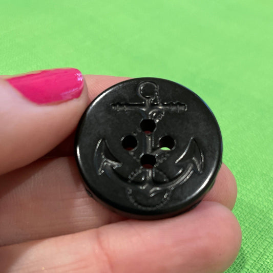 Black button held between fingers against a green background