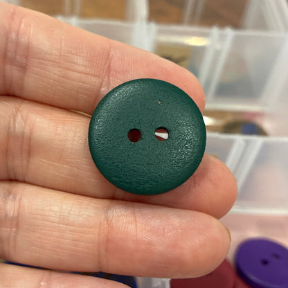 Green button held in hand with button collection in the background