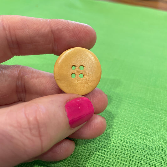 Hand holding a yellow button against a green background