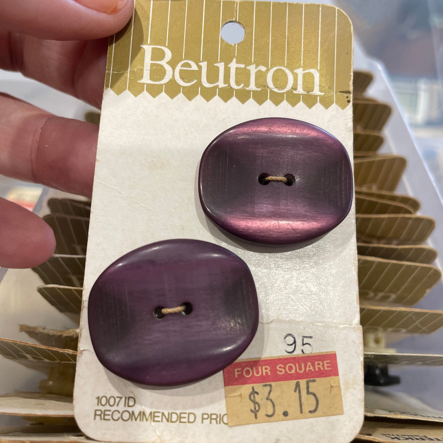 Purple buttons on a Beutron card held by a hand with a blurred background