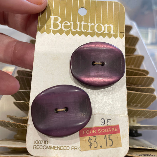 Purple buttons on a Beutron card held by a hand with a blurred background