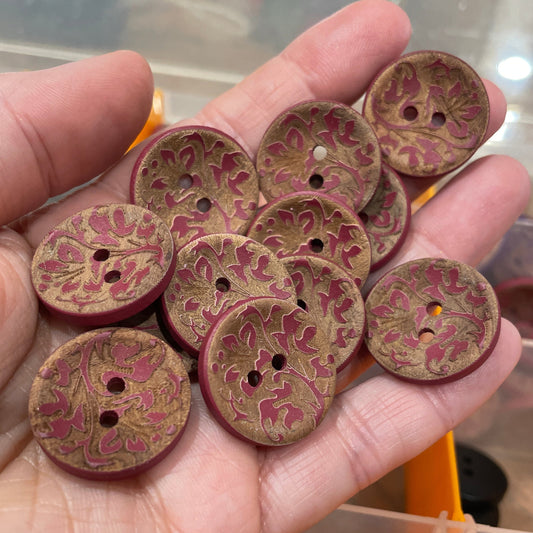 Hand holding a collection of patterned buttons with a blurred background