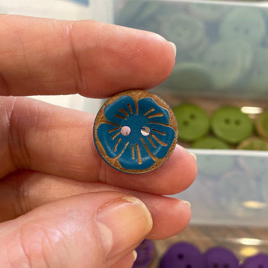 Hand holding a blue button with a background of button containers.